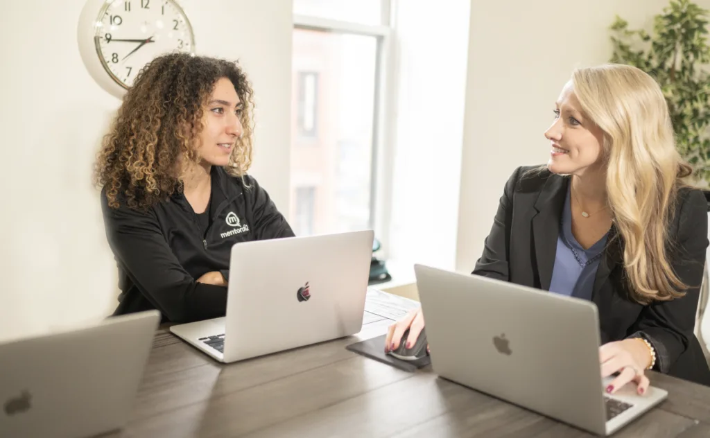 Two women talking at a table when peer mentoring.