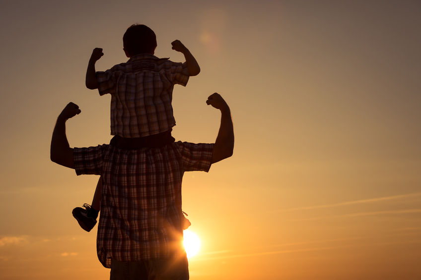 Father and son walking on the field at the sunset time. concept of family strength
