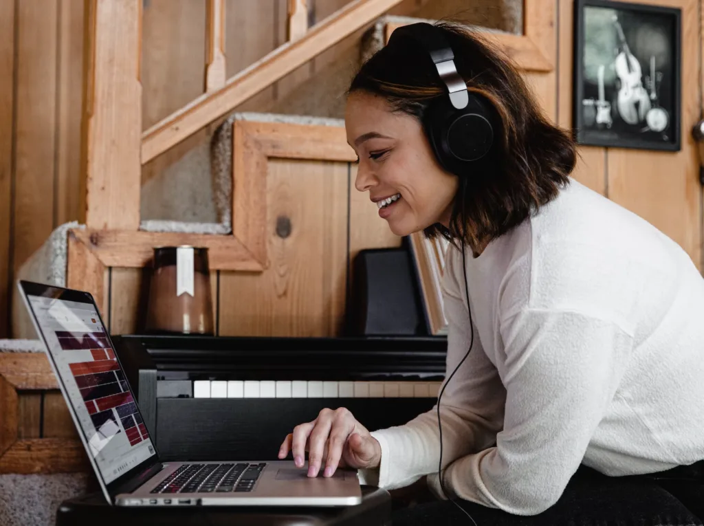A mentor working on their laptop wearing over the ear headphones in their home office.