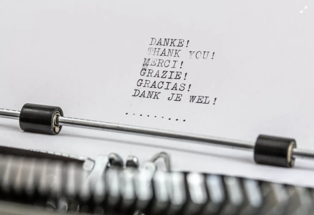 Paper in a typewriter that has the words thank you typed in different languages