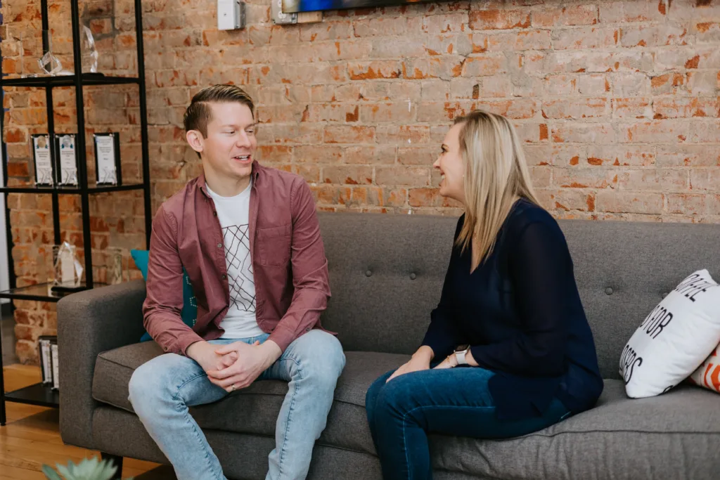 Man and women on a couch engaging in a mentor meeting conversation.