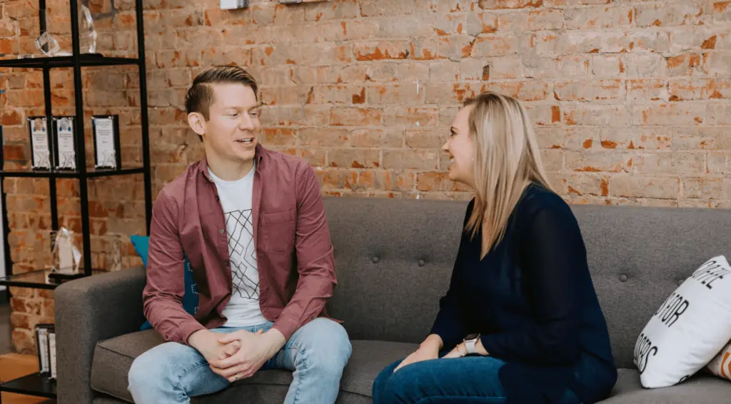 Two employees continuing a career conversation on a couch in an office setting.