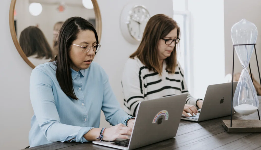 Two women at a table in an office setting.