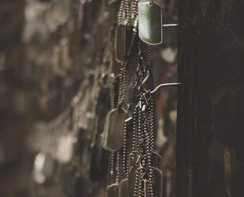 Rows of military dog tags hanging from chains in a dimly lit display.